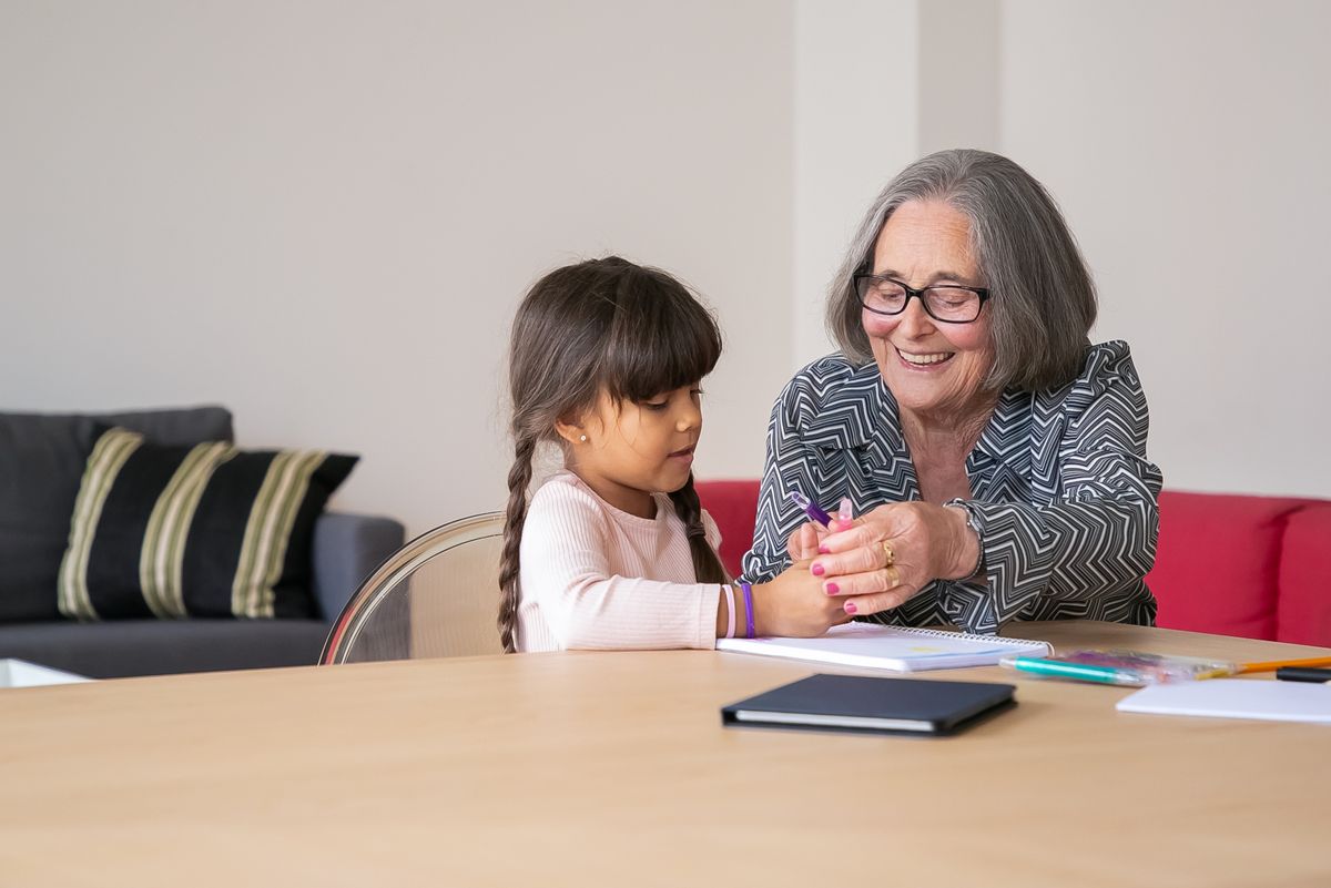An older woman and a child drawing together at a table